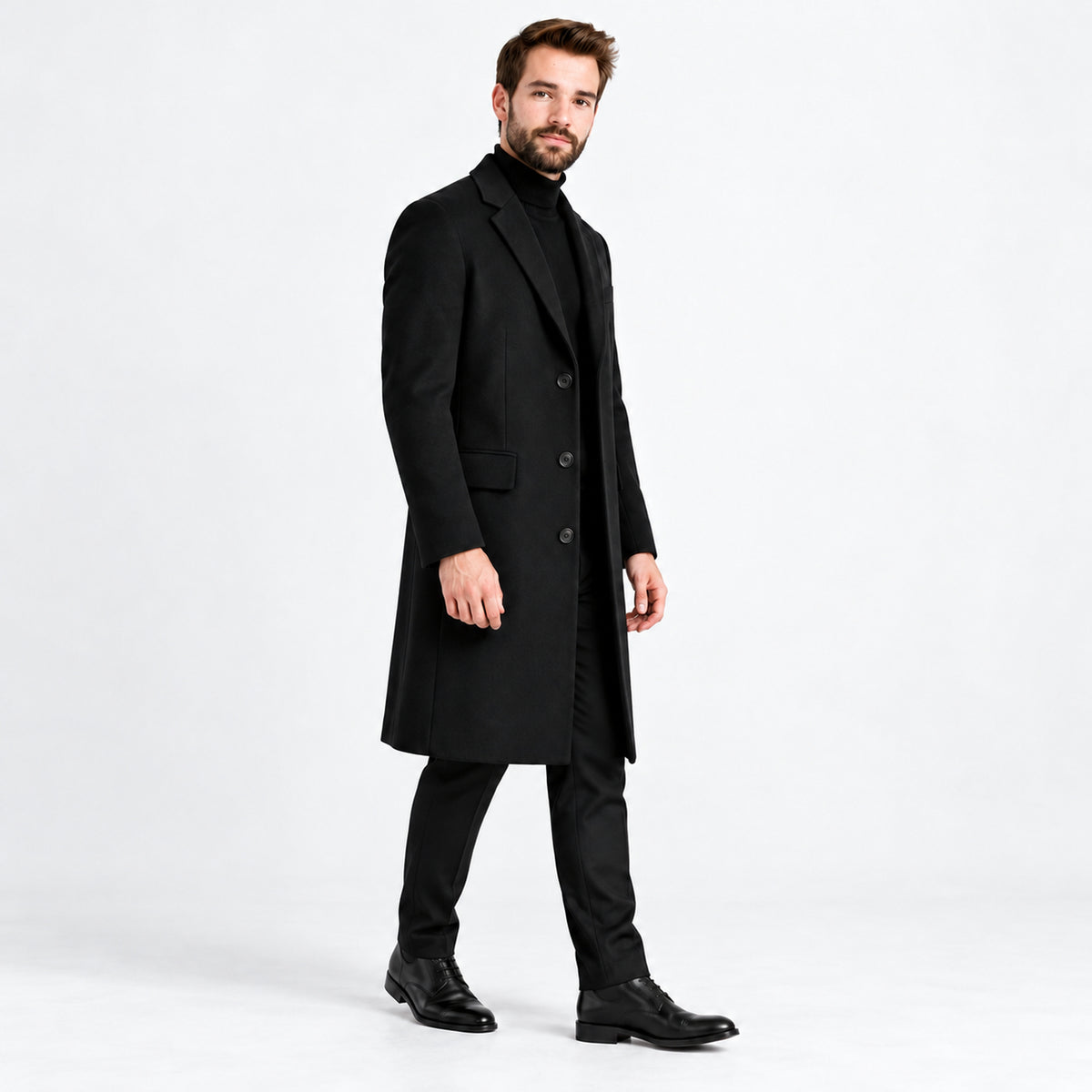 Homem usando sobretudo longo preto em nova pose de três quartos, fundo branco.